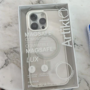 Vit MagSafe-kompatibel iPhone-skal - Säljer ett stilrent och genomskinligt hårt skal från Artikl till iPhone 15/14 Pro Max. Skalet är vitt med MagSafe-ring, har upphöjd kant runt kameran och funkar med trådlös laddning. Perfekt för dig som vill ha både skydd och snygg design. Helt oanvänd, säljer då jag köpt fel storlek:(       Nypris: 150kr