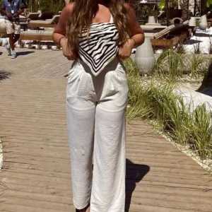 Zebramönstrad tubtopp i satin - Snygg tubtopp i bandeau-stil med svartvitt zebramönster. Toppen är sydd av ett glansigt satinliknande material och knyts i ryggen för en cool och trendig look. 