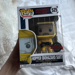 Hopper (Biohazard Suit) #525 - Cool Funko Pop! vinylfigur av Hopper i biohazard-dräkt från Stranger Things. Perfekt för fans av serien som vill ha något unikt i samlingen. Special Edition och officiell Netflix-merch – ett måste för dig som älskar spänning och mystik! Pris kan diskuteras!
