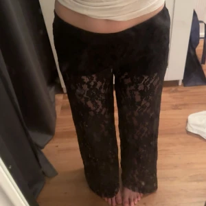 Svarta spetsbyxor med wide fit - Snygga svarta byxor i spets med transparenta ben och rak, lite vidare passform. Perfekta när du vill sticka ut och addera lite edge till din outfit. Mjukt material och elastisk midja för extra komfort. Passar perfekt på mig som är 160