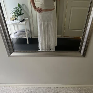 Vit långkjol med volang - Säljer en superfin vit långkjol med volangdetaljer, den går ändå ner till marken för mig som är 165 och år i storlek S💗