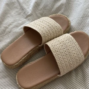 Beige flätade sandaler med platåsula - Snygga sandaler i beige med bred flätad rem över foten och plattformsula i repimitation. Perfekta för varma dagar och ger en chill sommarkänsla. Sulan är ribbad undertill för extra grepp. Lätta att matcha med allt. Dom är använda enstaka gånger, 
