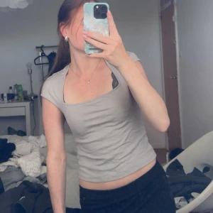 Beige croppad topp från H&M Divided - Säljer en beige croppad topp från H&M Divided med korta ärmar och fyrkantig urringning. Enkel och stilren design som är lätt att matcha med olika outfits. Perfekt för dig som gillar en clean och modern look.