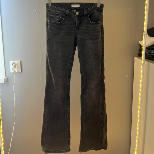 Mörkgrå bootcut jeans Gina Tricot - Snygga svarta bootcut jeans från Gina Tricot, modell Perfect Jeans. Jeansen har klassisk femficksdesign, coola bakfickor med lock och silverfärgade knappar. Materialet är stretchigt denim som sitter skönt och ger en schysst passform.
