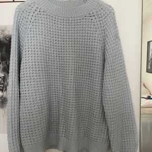 Ljusblå stickad tröja från Lager 157 - Säljer en ljusblå stickad tröja från Lager 157 i storlek L. Tröjan har ett grovt, luftigt stickat mönster och bred ribbad kant vid hals, ärmslut och nederkant.
