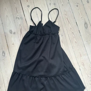 Svart kort klänning med volang - Snygg svart klänning från HM. Oanvänd!