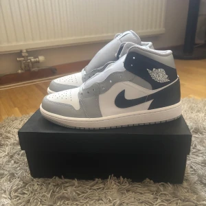 Nike Air Jordan 1 - Nypris: 1749 kr Säljer ett par Nike Air Jordan 1 Mid i färgerna grå, vit och marinblå. Skorna är i fint skick och kommer med originalkartongen, oanvända och endast testade en gång!