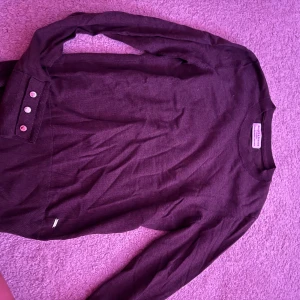 Mörkgrå långärmad tröja med knappar - Säljer en stilren mörkgrå långärmad tröja från Holly & White. Tröjan har rund halsringning och snygga knappdetaljer vid ärmsluten. Perfekt för dig som gillar en enkel men ändå trendig look.