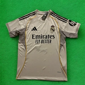 Real Madrid Mbappé fotbollströja Adidas - Snygg Real Madrid fotbollströja från Adidas med Mbappé och nummer 9 på ryggen. Tröjan är ljusgrå med svarta detaljer, gula linjer och klubbmärke på bröstet. Tillverkad i lätt funktionsmaterial med korta ärmar och klassiska Adidas-ränder på axlarna.