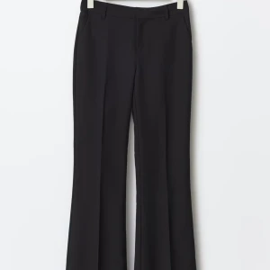 Svarta bootcut kostymbyxor Gina Tricot - Svarta kostymbyxor från Gina Tricot med bootcut-silhuett och pressveck. Byxorna har hällor för bälte och sidfickor. I modellen petite, passar för 1,60.