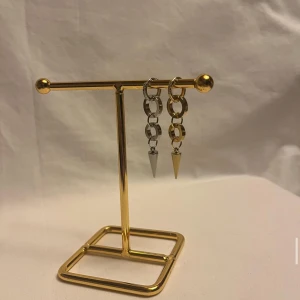 Chunky örhängen med kedjor och spikes - Säljer ett par statement örhängen i silver och guld med chunky kedjelänkar och coola konformade spikes längst ner. Örhängena har runda ringar upptill och ger en edgy vibe. Perfekta för dig som gillar att sticka ut med accessoarer.