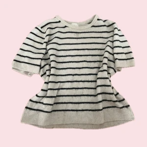 Randig stickad tröja från H&M - Superfin stickad tröja från H&M i vitt med svarta horisontella ränder. Tröjan har korta ärmar, rund halsringning och är gjord i ett mjukt stickat material. Använd och är lite knopprigt. 