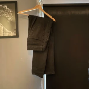 Svarta slim fit jeans från Dressmann - Svarta jeans från Dressmann i slim fit-modell. Klassisk femficksdesign och raka ben. Jeansen är tillverkade i ett mjukt och stretchigt bomullsmaterial som sitter snyggt och bekvämt hela dagen.
