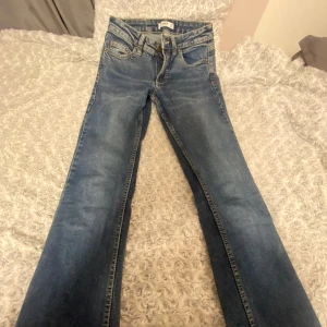 Blå jeans med ficklock och knappar - Snygga blå jeans från Zara med klassisk tvätt och coola bakfickor med lock och metallknappar. Jeansen har raka ben och normal passform, perfekta till en avslappnad streetstyle-look. Materialet är tåligt denim med kontrastsömmar.