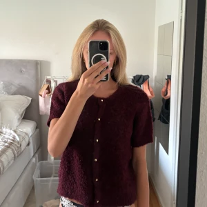 G(ullig) vinröd kofta från Gina Tricot  - Vinröd kofta med korta ärmar och guldiga knappar från Gina Tricot! I storlek XS men har stretchigt material så skulle säkert passa liten S också. Endast använd en gång så i mycket fint skick. Original pris är runt 400 kr, tror inte att den säljs längre! 