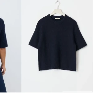 Mörkblå stickad tröja från gina(young) - Säljer en stilren mörkblå stickad tröja från Totême. Tröjan har korta ärmar och en klassisk rund halsringning. Perfekt för en avslappnad men elegant look. Använt 1 gång