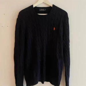  stickad tröja från Polo Ralph Lauren - Säljer en stilren stickad tröja från Polo Ralph Lauren med det klassiska logotypbroderiet i orange på bröstet. Storlek M men passar även L, pris kan diskuteras vid snabb affär!
