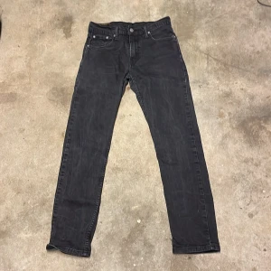 Svarta jeansbyxor från Levi's - Snygga svarta jeansbyxor från Levi's med klassisk femficksdesign och knappgylf. Perfekta för en stilren look. Passar till många olika outfits.