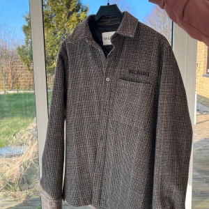 Jacka från Han Kjøbenhavn - medium  - Snygg rutig overshirt från Han Kjøbenhavn i jordnära färger. Jackan har en klassisk krage och en bröstficka. Perfekt för lager-på-lager-stil under kyligare dagar.