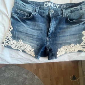 Jeansshorts med spetsdetaljer från ONLY - Snygga jeansshorts från ONLY med vackra spetsdetaljer på sidorna. De är blå och har en klassisk femficksdesign. Perfekta för en avslappnad sommarlook. 🩵