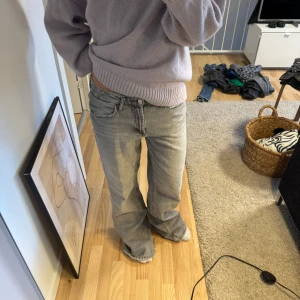 Grå jeans med bootcut - Säljer ett par grå jeans med bootcut-stil. De har en klassisk femficksdesign och är tillverkade i ett slitstarkt denimtyg. Perfekta för en avslappnad look.