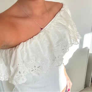 Vit offshoulder topp med spetsdetaljer - Säljer en söt vit offshoulder topp med spetsdetaljer. Toppen har en volangkant och är perfekt för sommarens varma dagar. Den är både stilren och romantisk. (lånade bilder)