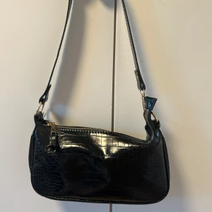 Svart axelremsväska purse - Säljer en svart axelremsväska som är ungefär 14*28cm. Jag har använt den ett fåtal gånger men det är i bra skick! Inga fläckar eller hål. Jag vet inte nypris men lägger ut för 150, vid snabb affär drar jag gärna ned priset 🥰Buda!