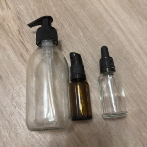 Kräm och serum behållare - Säljer tre tomma glasflaskor i olika storlekar. En stor genomskinlig flaska med svart pump, en mindre brun flaska med svart spraypump och en liten genomskinlig flaska med svart pipett. Perfekta för DIY-projekt eller förvaring av egna krämer och oljor! Kommer urtvättade!