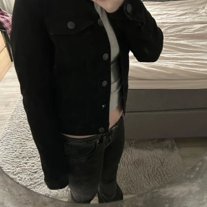 Svart jeansjacka - Snygg svart jeansjacka med knappar framtill och två bröstfickor. Jackan är croppad och har en klassisk design som passar perfekt till vardagsoutfiten.