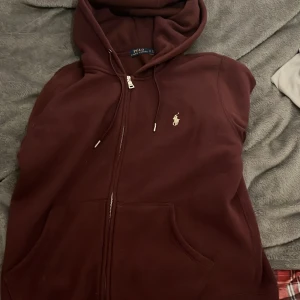 Vinröd hoodie från Ralph Lauren - Säljer en snygg vinröd hoodie från Ralph Lauren med dragkedja. Den är Ej använd och skulle rekomendera att köpa om du har storlek Xs-S. Eftersom att den är för liten för mig. Dessutom så är den bara använd 3 gånger.