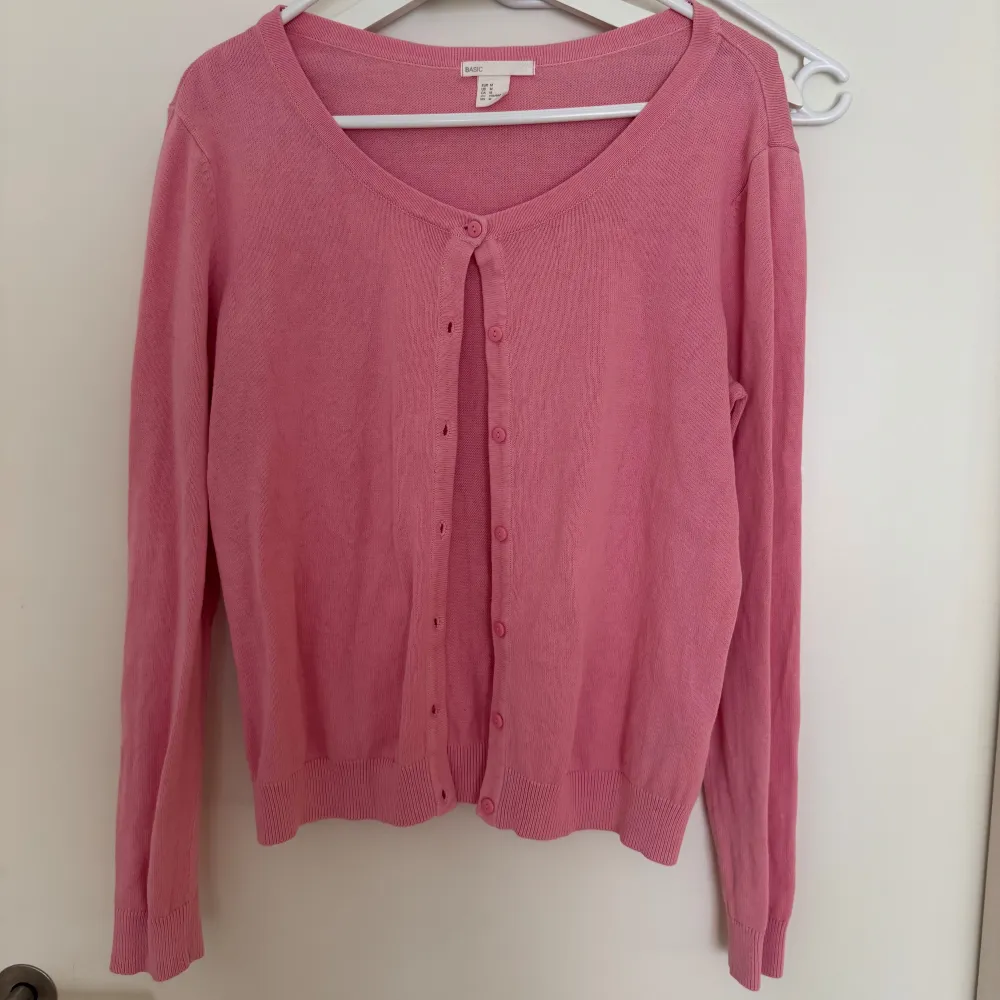Säljer en söt rosa kofta från Basic med knappar framtill. Koftan har en rund halsringning och långa ärmar. Perfekt för att lägga till en färgklick i din garderob!. Neuletakit & Villapaidat.