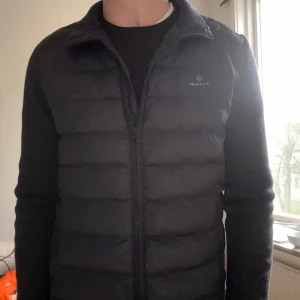 Marinblå cardigan  från GANT - Snygg marinblå cardigan från GANT med dragkedja framtill. Jackan har långa ärmar och en stilren design, perfekt för kyligare dagar. Den quiltade stilen ger en modern look. Nypris 2800 kr