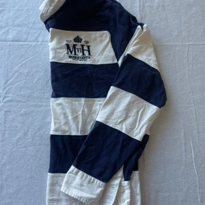 Randig pikétröja från Morris - Säljer en snygg randig pikétröja från Morris i marinblått och vitt. Tröjan har långa ärmar med bruna armbågslappar och en klassisk krage. Perfekt för en stilren look! 🏷️ 