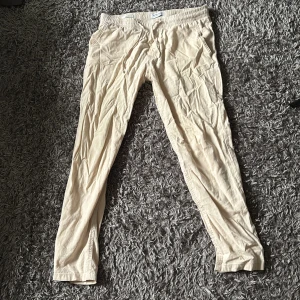 Beiga linnebyxor från Jack & Jones - Snygga beiga linnebyxor från Jack & Jones med elastisk midja och dragsko. Lätta och sköna, perfekta för chill dagar. Byxorna har raka ben och sidfickor. Passar dig som gillar en avslappnad stil.