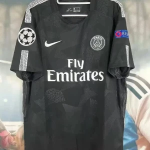 Svart PSG fotbollströja Nike - Snygg svart PSG fotbollströja från Nike med Fly Emirates-tryck på bröstet och Champions League-märke på ärmen. Tröjan har korta ärmar och diskreta mönster i tyget samt klubbmärke på bröstet. Perfekt för dig som älskar fotboll och vill sticka ut på planen.