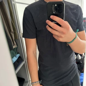 Svart t-shirt från vailent  - En stilren svart t-shirt från vailent med klassisk rund hals och korta ärmar. T-shirten är gjord i mjuk bomull och har en normal passform som sitter snyggt på kroppen. Perfekt för dig som gillar enkla och cleana plagg i garderoben. Jag är 181cm och 75kg