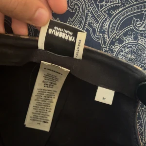 Burberry keps - Säljer en klassisk Burberry keps i beige med ikoniskt rutigt mönster och svart justerbar snapback. Kepsen har tydlig Burberry London England patch baktill och är tillverkad i bomull och polyester. Perfekt för dig som vill ha en snygg och tidlös streetstil. Varför jag just säljer denna kepsen är för att jag tar inte på mig kepsar längre