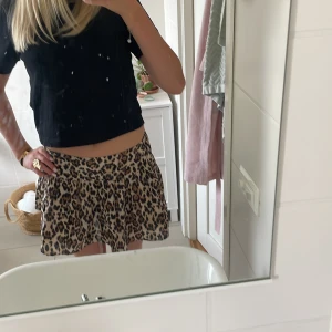 Leopardmönstrad kortkjol med volang - Säljer en kort kjol med leopardmönster i beige och bruna toner. Kjolen har en lätt volang och sitter snyggt i midjan. Perfekt för dig som vill sticka ut med ett djuriskt print och gillar en flowy känsla.