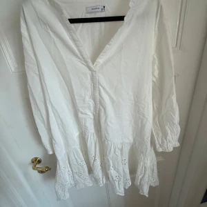 Vit sommarklänning - Supersöt vit sommarklänning från Reserved i storlek 38. Klänningen har v-ringning, långa ärmar med resår vid handlederna och volangkant med broderad spets längst ner. Tyvärr för kort på mig