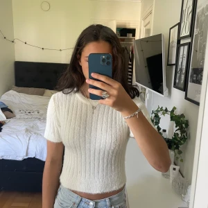 Vit ribbad stickad tröja från Zara - Superfin vit stickad tröja från Zara med kort ärm och croppad passform. Tröjan har ribbat mönster och rund halsringning, perfekt till jeans eller kjol. Jättemjuk och fluffig.