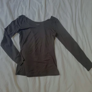 Svart långärmad topp - Svart långärmad tröja i storlek XS. Tröjan har en rundad halsringning och är tillverkad i ett tunt, stretchigt material som passar perfekt för lager-på-lager under kyliga dagar. Något kort i armarna