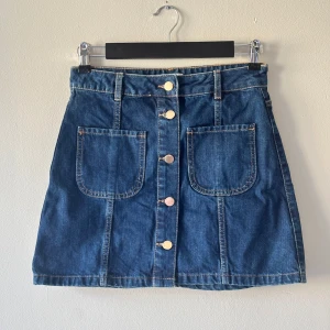 Jeanskjol med knappar från River Island - Snygg mörkblå jeanskjol från River Island. Aldrig använd!