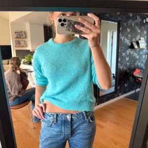 Turkos stickad tröja från Parfois - Mysig turkos stickad tröja från Parfois med rund hals och ribbade muddar. Modellen är lite croppad och har långärmade ärmar. Perfekt att slänga på sig när du vill ha en chill och färgglad look. Supermjuk och skön mot huden.