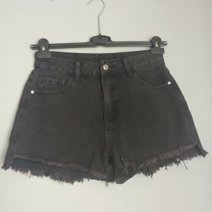 Snygga svarta jeansshorts från SHEIN i storlek Petite M. - Snygga svarta jeansshorts från SHEIN i storlek Petite M.  Klassisk femficksmodell  Hög midja  Rå, fransig fåll för en avslappnad look  Knapp- och dragkedjestängning  Material: 70% bomull, 24% polyester, 6% viskos   Shortsen är i gott skick och perfekta till sommaren, festivalen eller en vardaglig streetstyle-outfit.