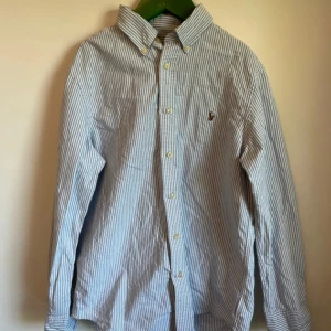 randig skjorta från Ralph Lauren - Snygg randig skjorta från Ralph Lauren med klassisk krage och broderad logga på bröstet. Skjortan är i fint skick då den inte är använd så mycket nypris= 2000 kr mitt =249 kr, skriv om minsta lilla fundering!
