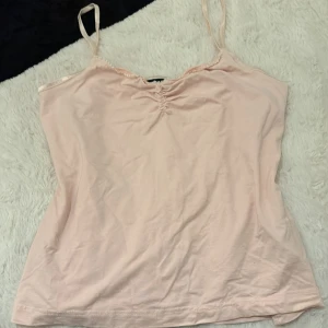 Ljusrosa linnetopp med smala axelband - Supersöt ljusrosa linnetopp med smala axelband och lätt rynkning vid halsringningen. Mjuk och tunn bomull som känns skön mot huden.