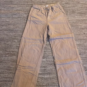 Beiga raka byxor i bomull - Snygga beiga byxor med raka ben och klassisk femficksdesign. Tillverkade i mjuk bomull, perfekta för en chill och stilren look. Passar dig som gillar enkel och clean stil. Bälteshällor och bakfickor för extra funktion.