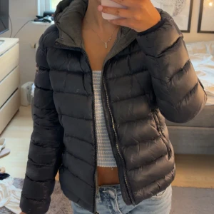 Mörkblå jacka från Colmar - Säljer en mörkblå dunjacka från Colmar med quiltad design och dragkedja framtill. Jackan har huva, två fickor med dragkedja och en snygg logga på ärmen. Perfekt för kalla dagar och riktigt skön att bära. Storlek 44 men skulle säga att den sitter som S.