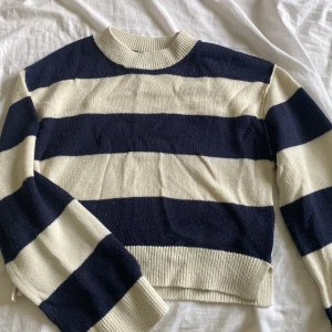 Randig stickad tröja från Divided H&M - Säljer en stickad tröja från Divided H&M i storlek XXS. Tröjan har breda marinblå och vita ränder, rund halsringning och ribbade muddar. Perfekt för dig som gillar en klassisk och chill stil. Den lite nopprig.