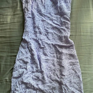 Ljuslila blommig klänning och kjol - Supersöt ljuslila klänning från Friday med små blommor i mönstret. Klänningen är kort, har smala axelband och en dragkedja i ryggen. Materialet är mjukt och känns som bomull, perfekt för varma dagar. Den har en feminin passform och volangdetalj upptill.    Det var en lång klänning från början som en sömmerska sytt om till två delar, en kort klänning och en kjol. Båda två ingår såklart.